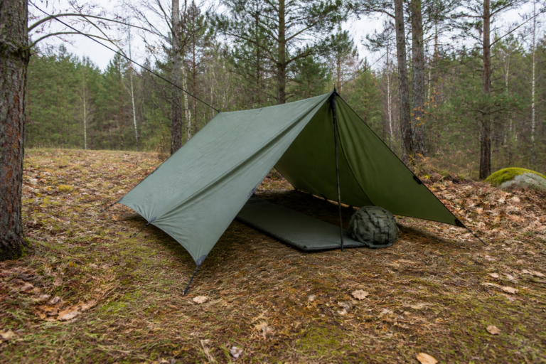 Sicher aufgebaute Notunterkunft mit Tarp und Isomatte im Wald