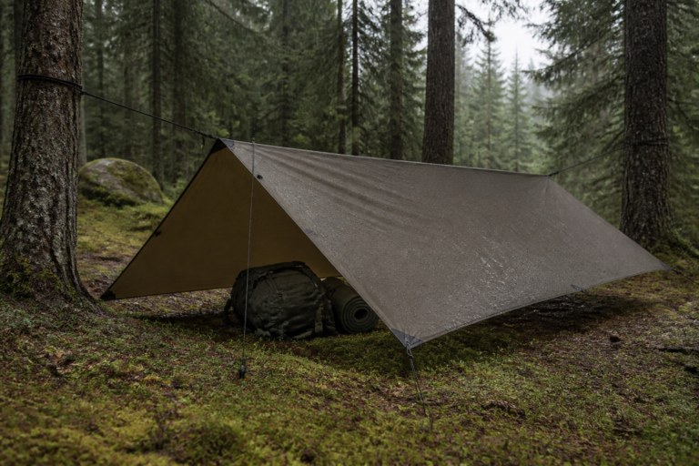 Tarp als Notunterkunft mit Notfallrucksack und Isomatte im Wald